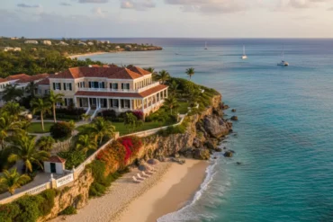 Luxury beachfront villa at Inchcape in Barbados overlooking turquoise Caribbean waters, surrounded by palm trees, lush gardens, and white sandy beach at sunset.